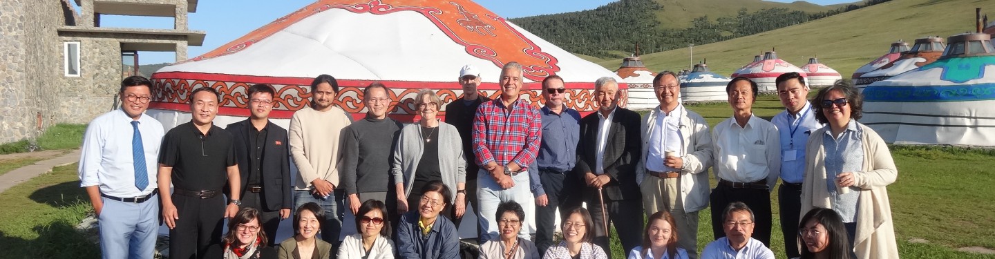 A group of people standing in front of a Mongolian hut