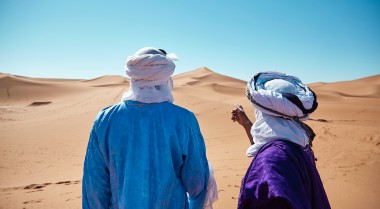 Two men standing in the dessert pointing at the horizon